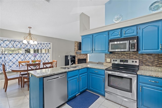 kitchen featuring stainless steel appliances, pendant lighting, light tile patterned floors, blue cabinets, and light stone counters