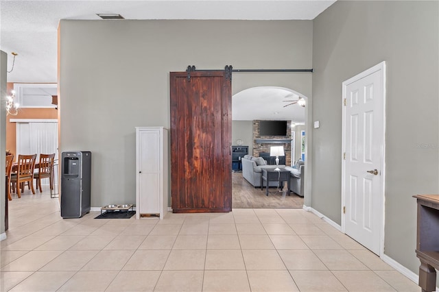 interior space with a high ceiling, a barn door, a notable chandelier, and light tile patterned floors