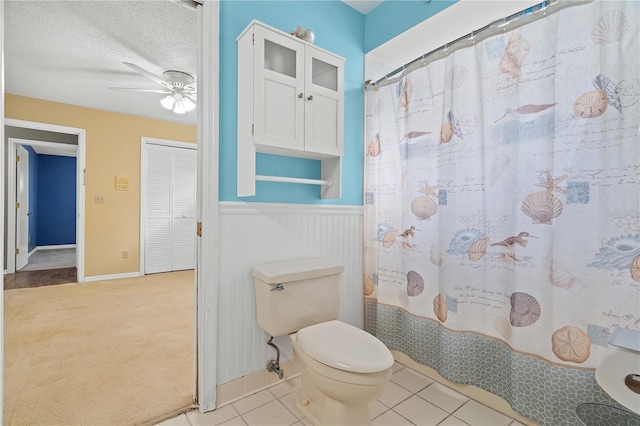 bathroom with ceiling fan, a textured ceiling, walk in shower, toilet, and tile patterned flooring