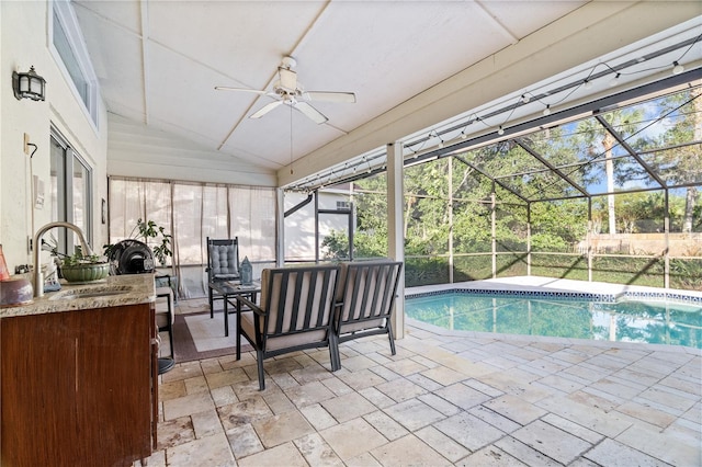 view of swimming pool featuring sink, a patio area, glass enclosure, and ceiling fan