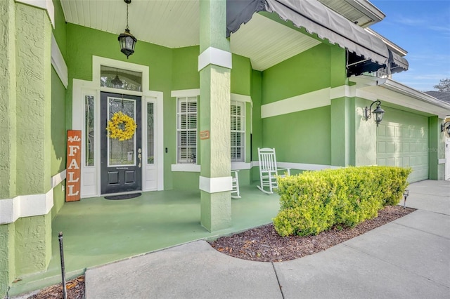 property entrance with a garage, stucco siding, concrete driveway, and a porch