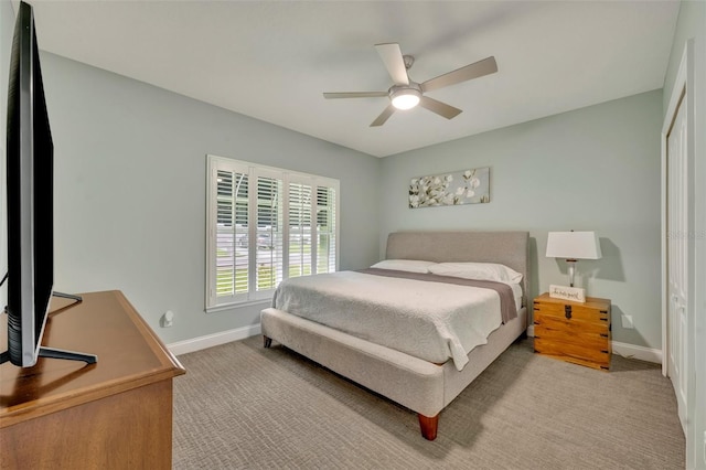 bedroom with baseboards, a ceiling fan, a closet, and light carpet