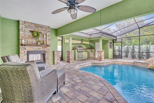 view of swimming pool featuring ceiling fan, a stone fireplace, and grilling area