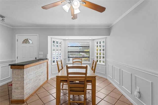 tiled dining room featuring ceiling fan and ornamental molding