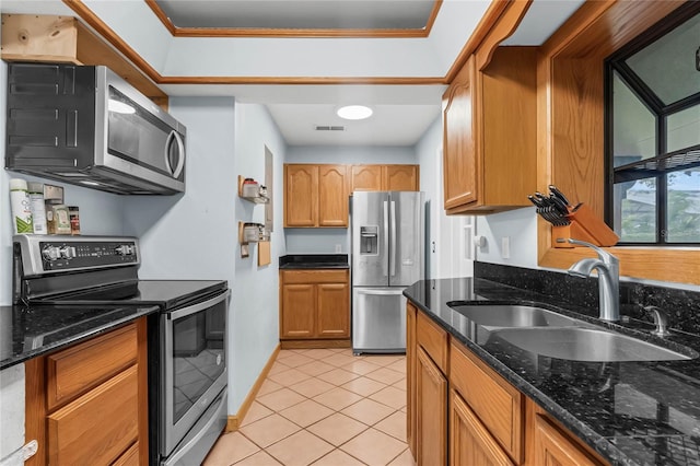 kitchen featuring stainless steel appliances, light tile patterned flooring, sink, ornamental molding, and dark stone countertops