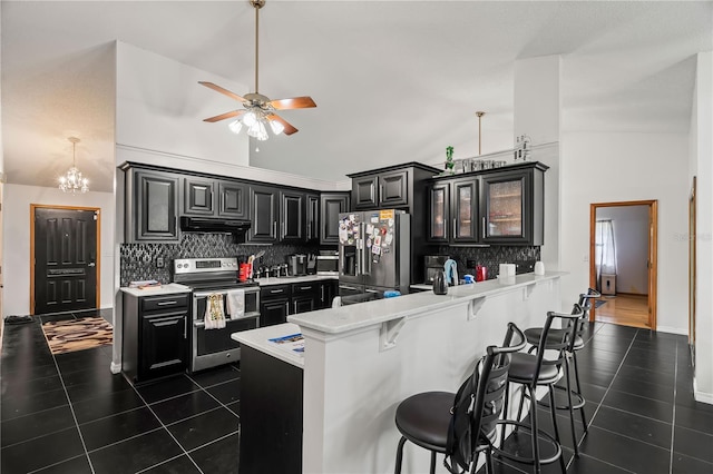 kitchen with kitchen peninsula, high vaulted ceiling, appliances with stainless steel finishes, and a kitchen bar