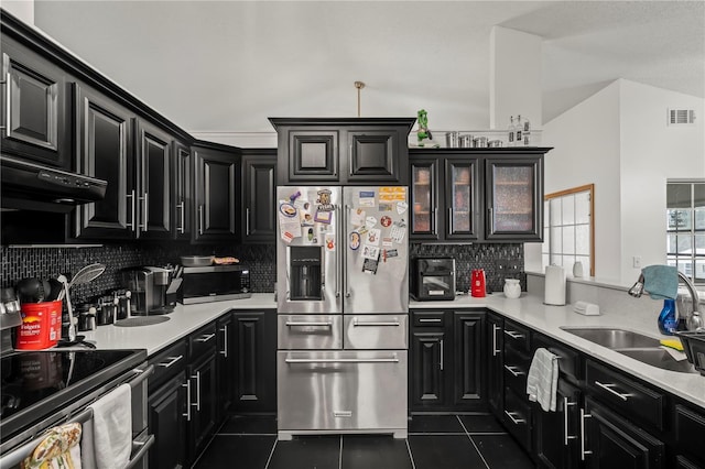 kitchen with dark tile patterned flooring, stainless steel appliances, range hood, vaulted ceiling, and tasteful backsplash