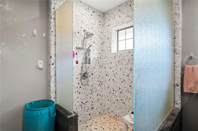 bathroom with a tile shower and toilet