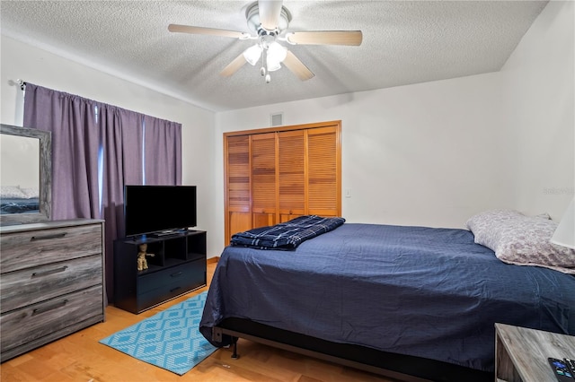 bedroom with a closet, a textured ceiling, light wood-type flooring, and ceiling fan