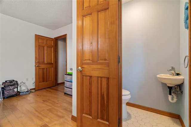 bathroom featuring sink, a textured ceiling, wood-type flooring, and toilet