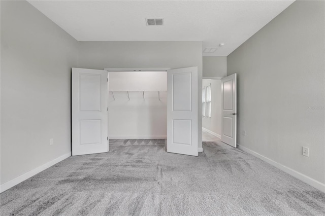 unfurnished bedroom featuring light colored carpet and a closet