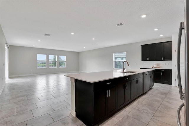 kitchen featuring sink, dishwasher, an island with sink, and light tile patterned floors