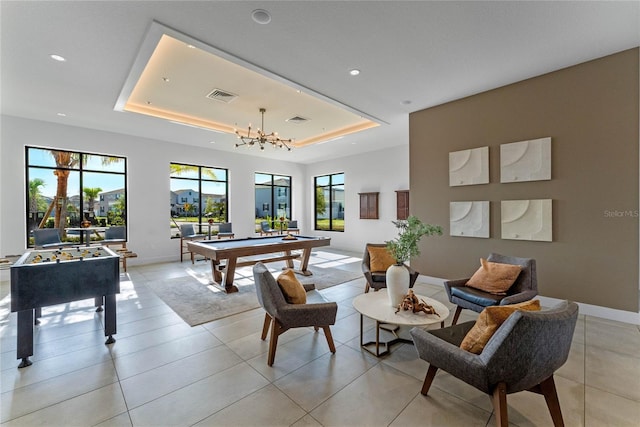 game room with a tray ceiling, billiards, a chandelier, and light tile patterned flooring