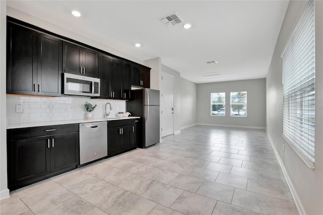 kitchen with light tile patterned floors, stainless steel appliances, sink, and backsplash