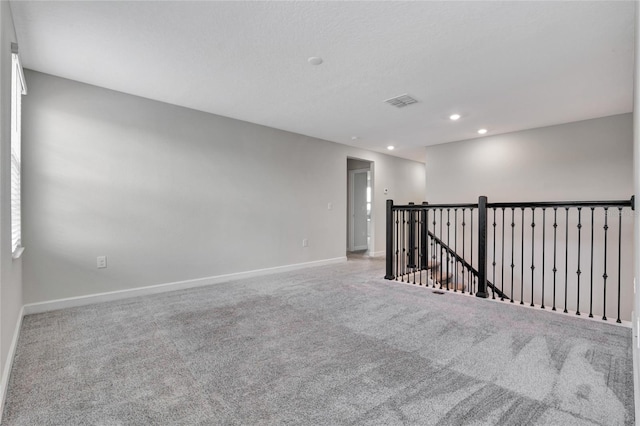 spare room featuring light carpet, visible vents, baseboards, and recessed lighting