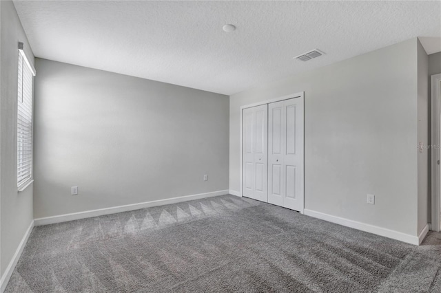 unfurnished bedroom with carpet floors, a closet, and a textured ceiling