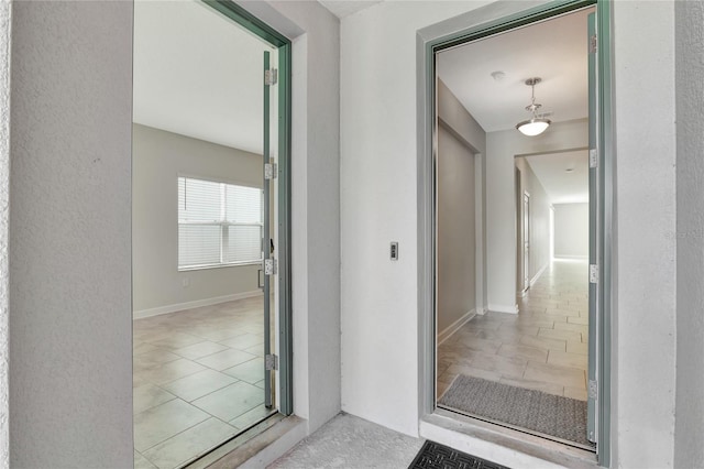 hall with light tile patterned floors and baseboards