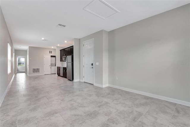 unfurnished living room featuring attic access, visible vents, and baseboards