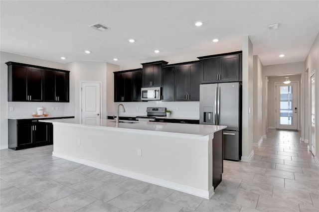 kitchen featuring stainless steel appliances, a sink, visible vents, light countertops, and an island with sink