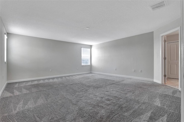 carpeted empty room featuring a textured ceiling, visible vents, and baseboards