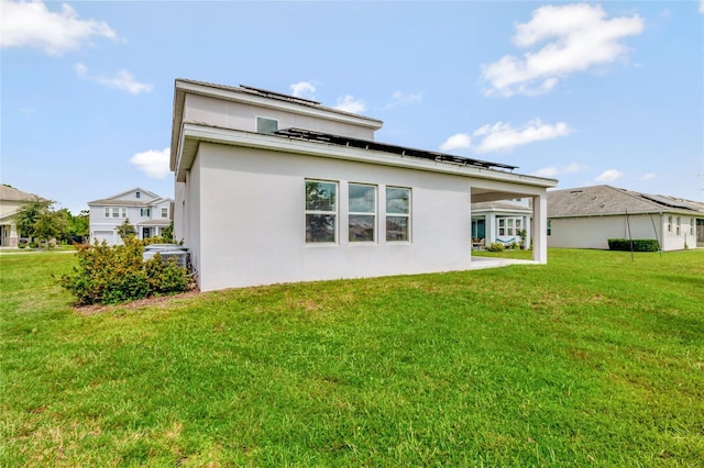 rear view of house with stucco siding and a yard