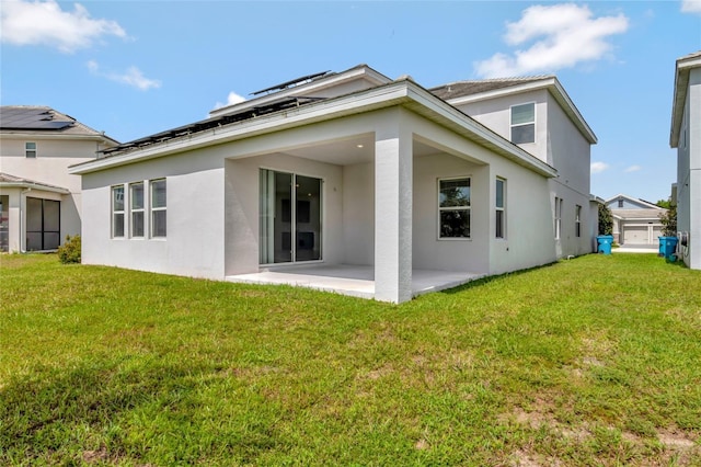 rear view of house featuring stucco siding, a patio, and a lawn