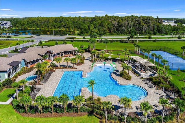 pool featuring a patio, a water view, and fence