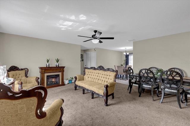 carpeted living room featuring ceiling fan with notable chandelier