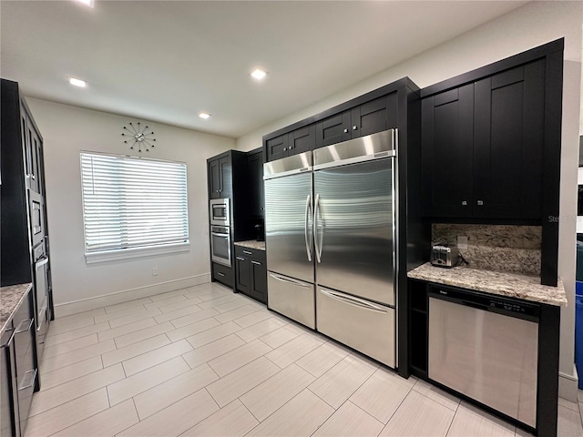 kitchen with built in appliances, tasteful backsplash, and light stone countertops