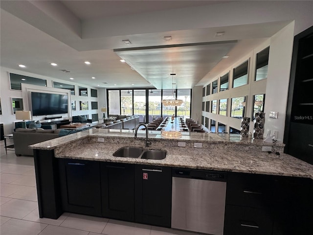 kitchen featuring a wealth of natural light, stainless steel dishwasher, sink, and light stone countertops