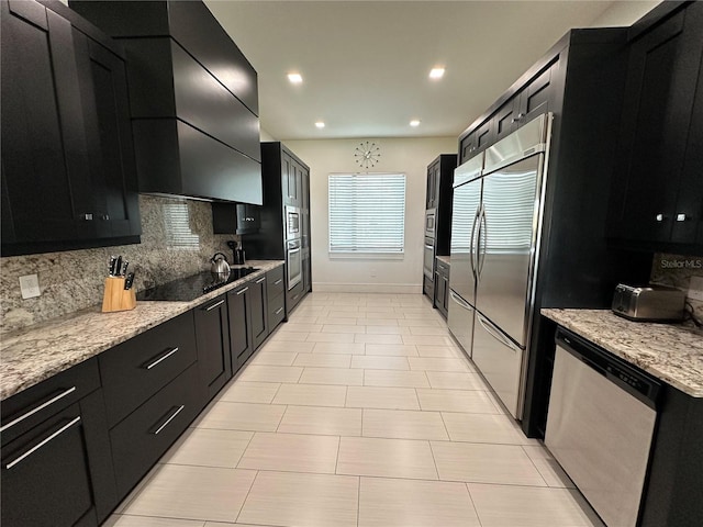 kitchen featuring light stone countertops, decorative backsplash, wall chimney range hood, and stainless steel appliances