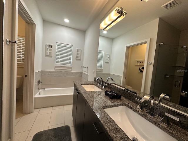 full bathroom featuring tile walls, tile patterned floors, shower with separate bathtub, vanity, and toilet