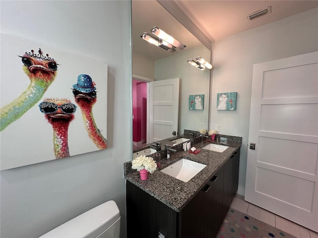 bathroom with tile patterned flooring, vanity, and toilet