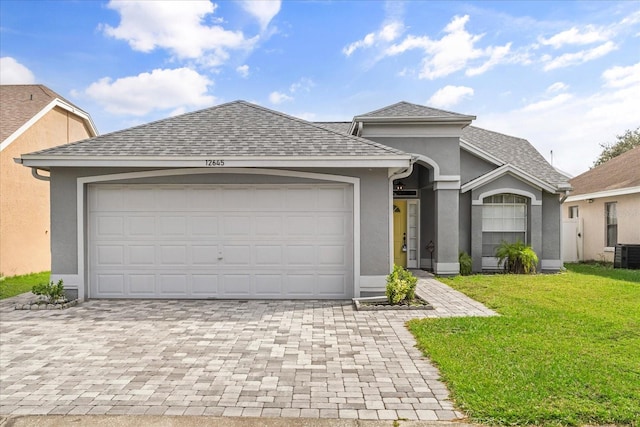 view of front of property featuring cooling unit, a front lawn, and a garage