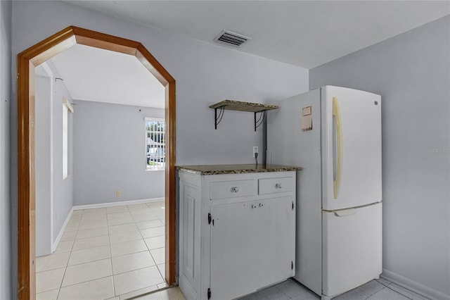 kitchen with white cabinets, light tile patterned floors, and white refrigerator