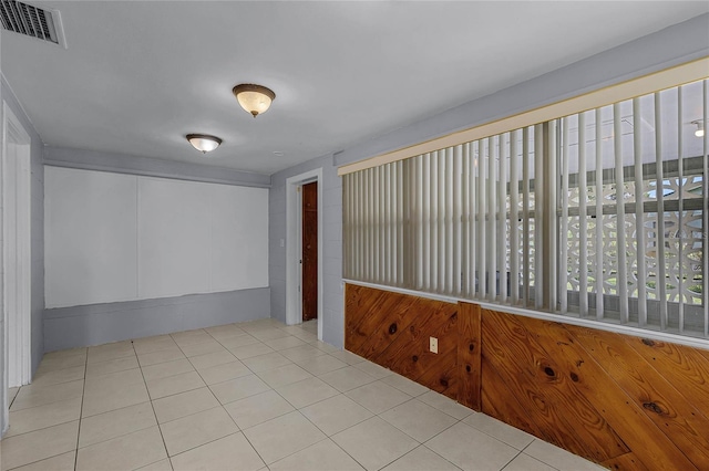 spare room featuring wood walls and light tile patterned flooring