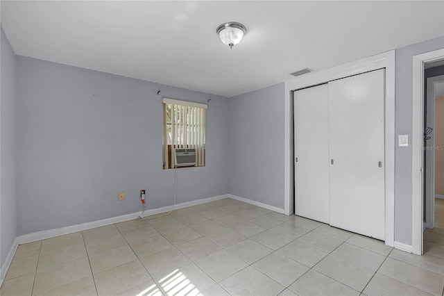 unfurnished bedroom with a closet, cooling unit, and light tile patterned floors