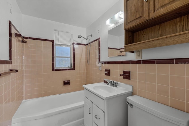 full bathroom with toilet, tiled shower / bath, vanity, and tile walls