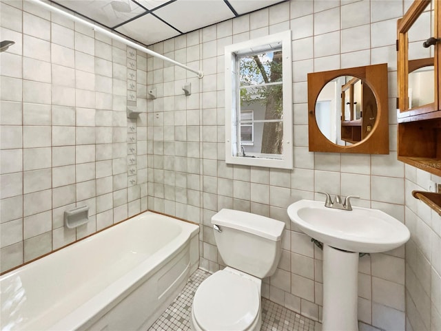 bathroom with toilet, tiled shower / bath, tile patterned floors, and tile walls