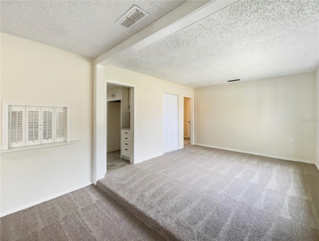 spare room featuring a textured ceiling and carpet flooring