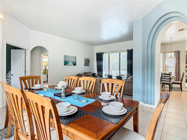 tiled dining area featuring a textured ceiling and a chandelier