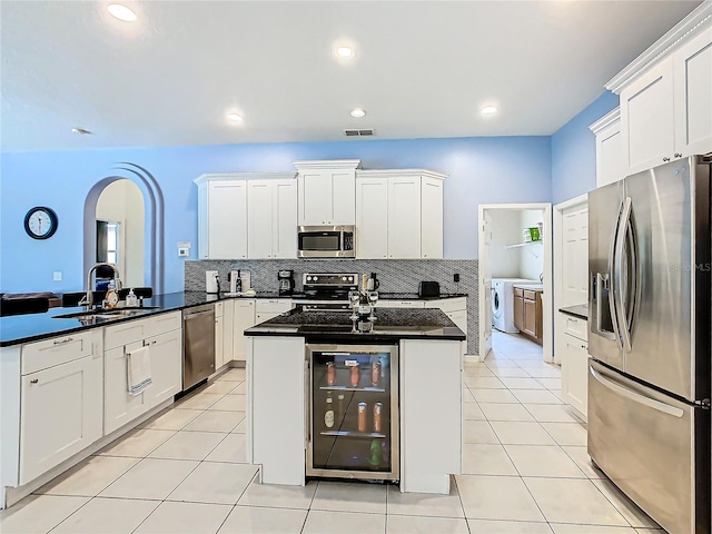 kitchen featuring kitchen peninsula, sink, white cabinetry, beverage cooler, and appliances with stainless steel finishes