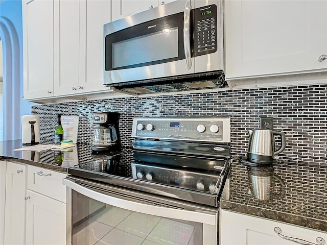 kitchen with black stove, white cabinetry, and backsplash