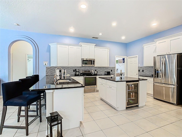 kitchen featuring a kitchen island, wine cooler, sink, white cabinetry, and appliances with stainless steel finishes