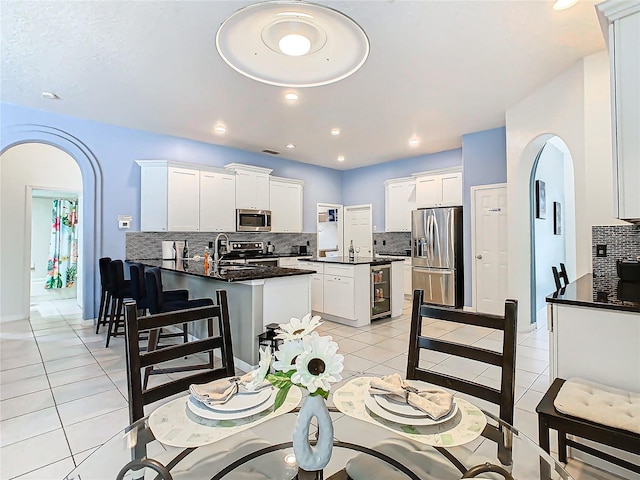 kitchen with appliances with stainless steel finishes, white cabinets, and an island with sink