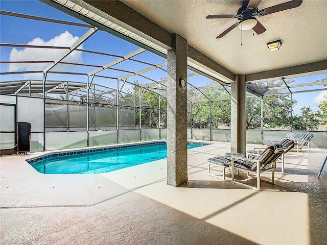 view of pool with a patio, glass enclosure, and ceiling fan