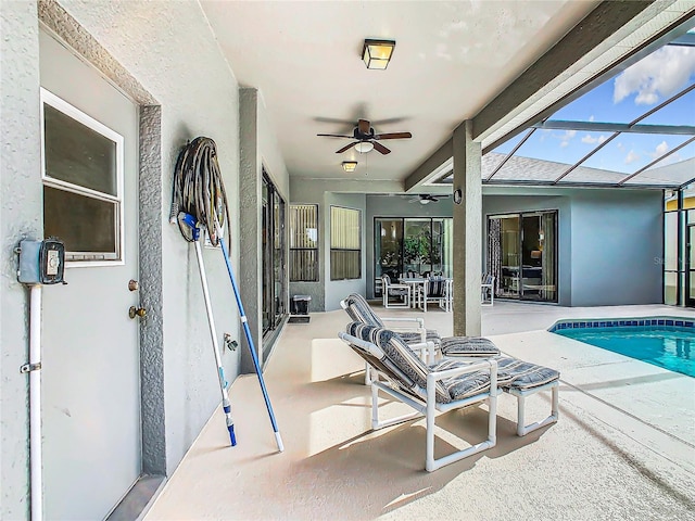 view of swimming pool featuring ceiling fan, glass enclosure, and a patio area