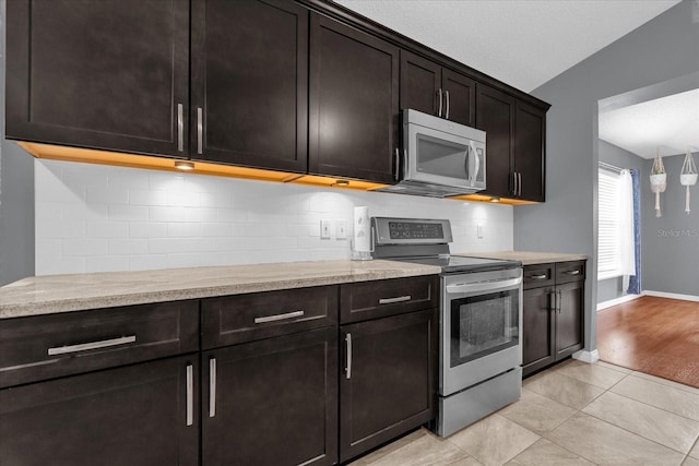 kitchen with appliances with stainless steel finishes, light wood-type flooring, backsplash, a textured ceiling, and vaulted ceiling