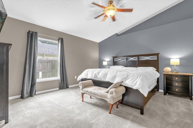 bedroom with a textured ceiling, vaulted ceiling, light colored carpet, and ceiling fan