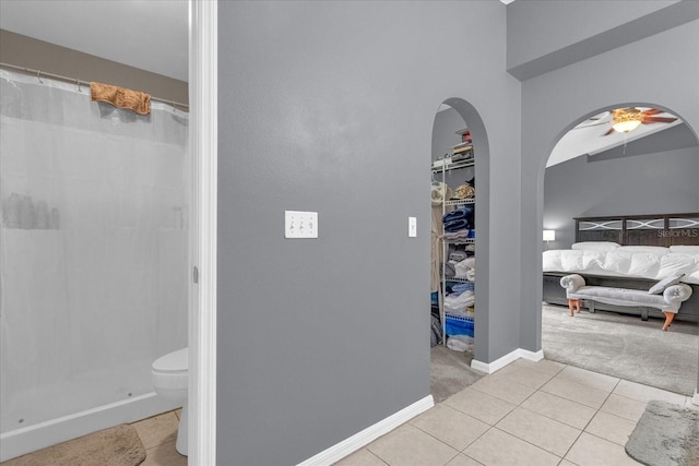 bathroom with toilet, a shower with curtain, tile patterned floors, and ceiling fan